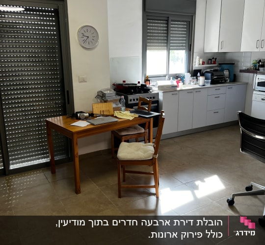 מטבח עם שולחן עץ, כיסאות וציוד ארוז למעבר
